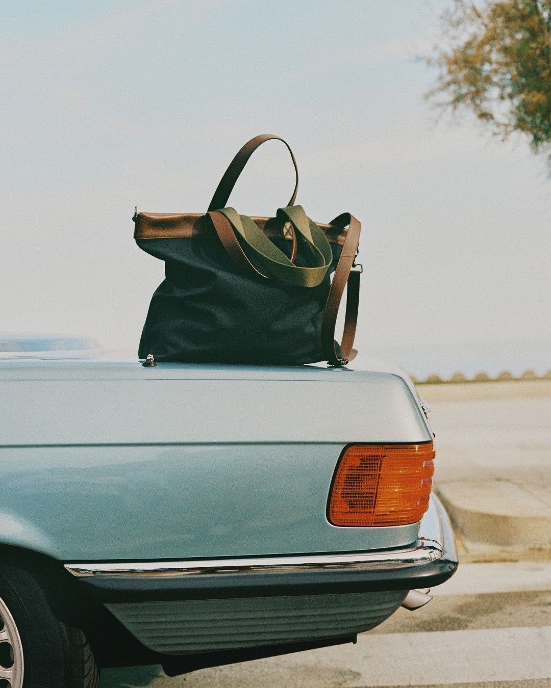 Black weekend bag resting on the trunk of a vintage car
