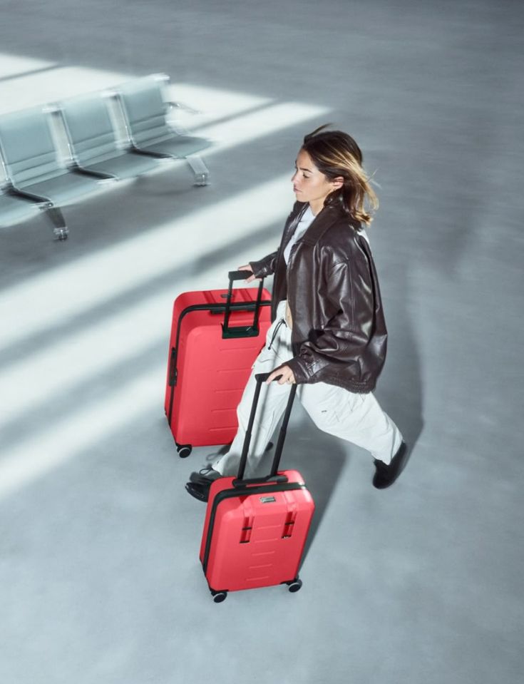 Traveler walking through an airport with two red suitcases