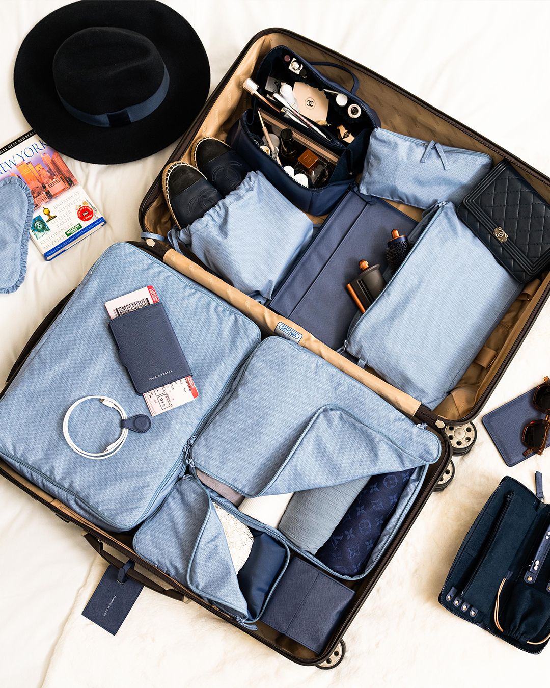 Suitcase arranged with blue packing cubes and travel accessories